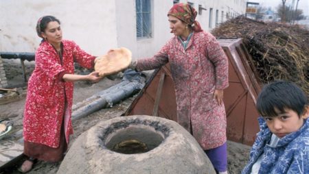 Женщины пекут лепешки в тандыре на улице села Муграб